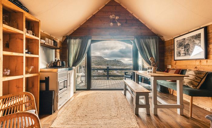 Interior of llechwedd glamping tent showing kitchenette, dining table and views of the moutnains outsite